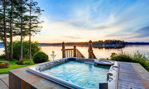 Awesome water view with hot tub in summer evening. House exterior.